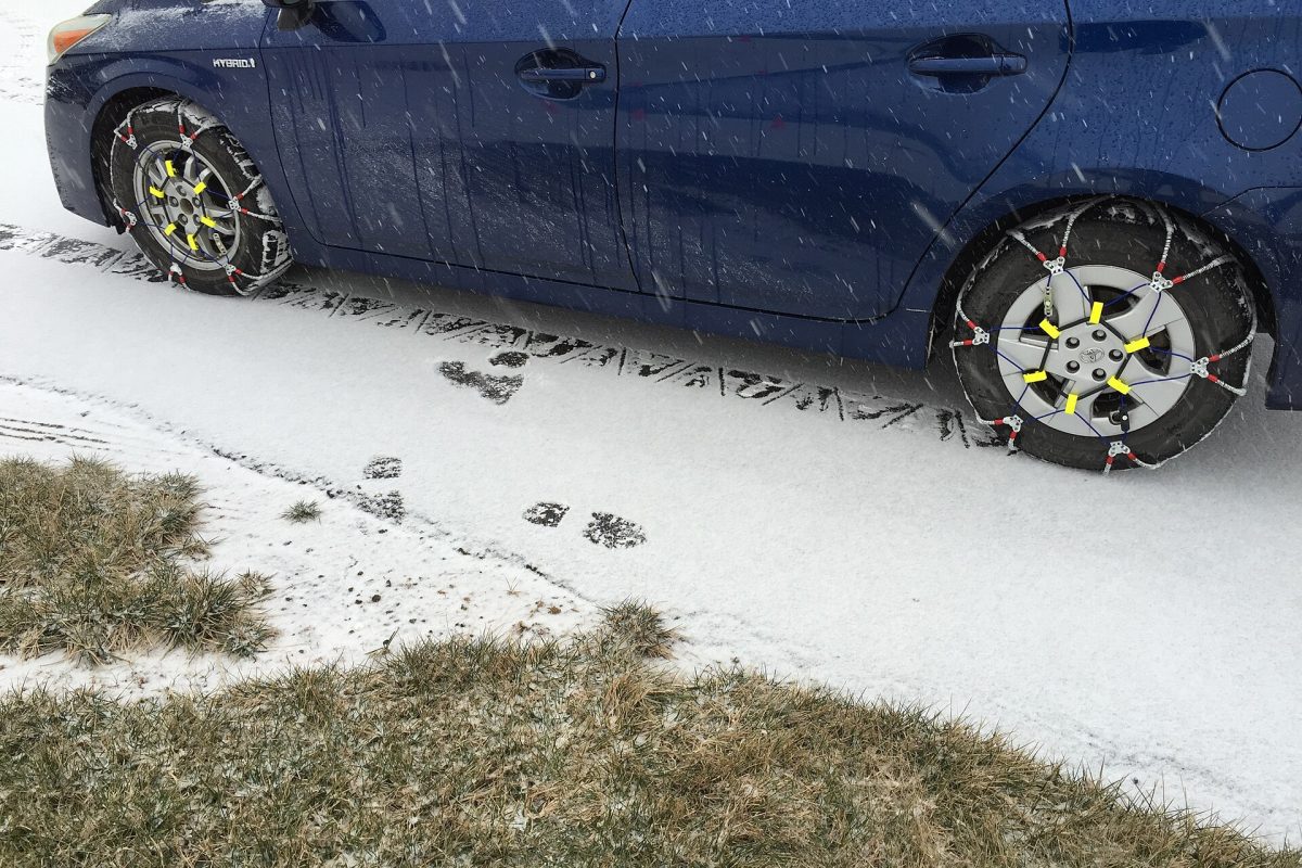 Chaînes à neige montées sur les roues d’une voiture, sur route enneigée