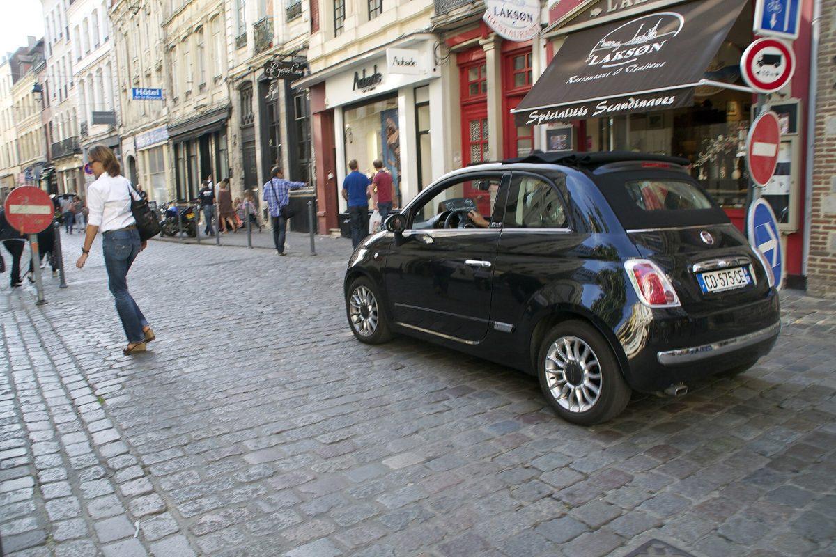 Petite voiture circulant dans une rue pavée de centre-ville